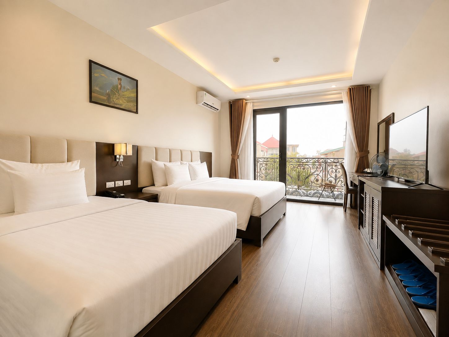 A hotel room with two beds, a TV, a balcony with a view, and an air conditioning unit.
