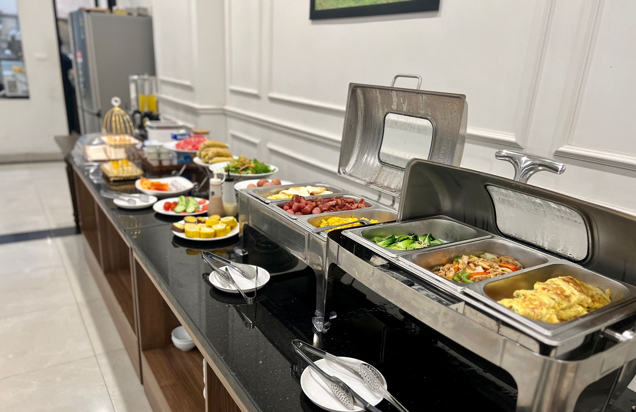 Montaje de desayuno tipo buffet con diversos alimentos y utensilios.