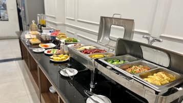 Montaje de desayuno tipo buffet con diversos alimentos y utensilios.