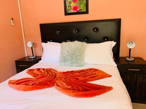 A neatly made bed with a decorative blanket, a fluffy pillow, and a framed picture on the wall. - RS Garden Guesthouse (Thohoyandou)