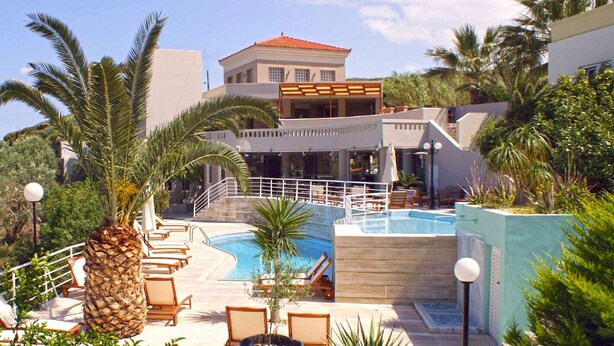 Un complexe hôtelier doté d’une piscine, de chaises longues et d’un bâtiment au toit rouge.