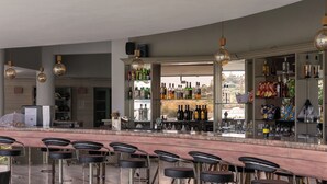 Un espace bar doté de plusieurs tabourets, d’un comptoir avec les ustensiles nécessaires et d’étagères remplies de bouteilles et d’en-cas.