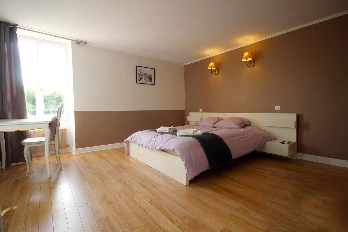 A bedroom with a bed, bedside table, chair, and two wall-mounted lamps.