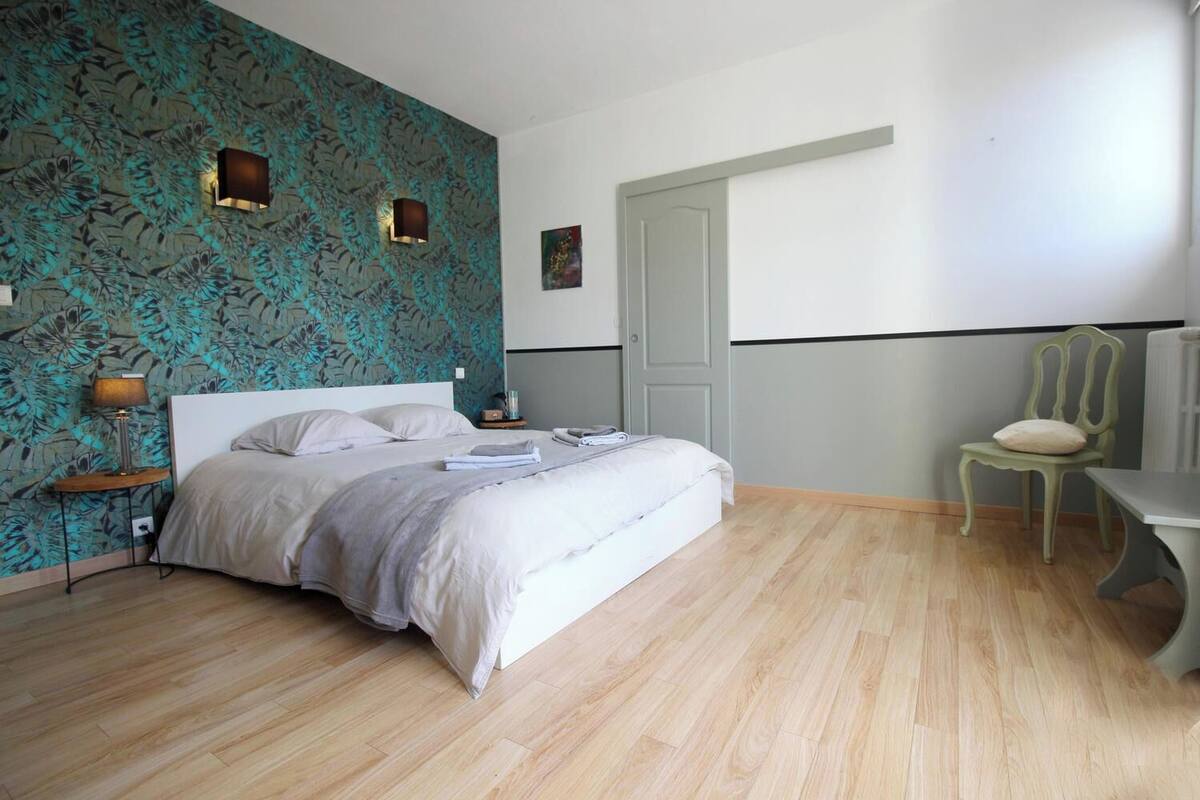 A bedroom with a bed, a nightstand, a chair, and a door.