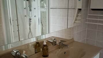 Ein Badezimmer mit einem Doppelwaschbecken, einer Duschkabine aus Glas und einem Händetrockner.
