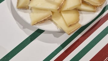 Ein Teller mit Käse und Crackern, beschriftet mit 'VACHE' und 'BEBE', auf einer gestreiften Tischdecke.