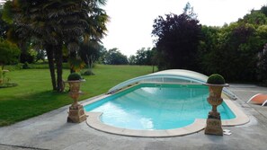 Una piscina al aire libre de temporada, sombrillas