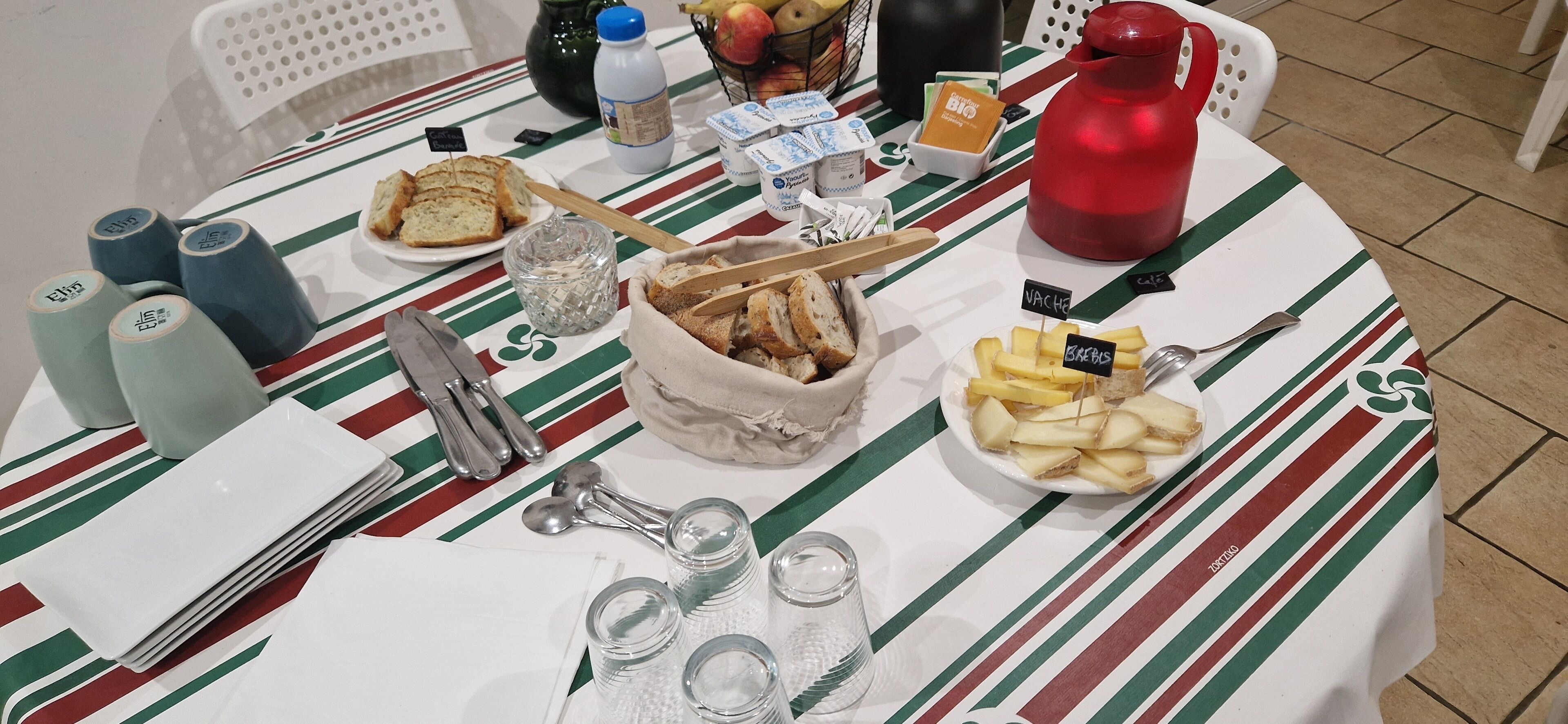 A table with various food items, utensils, and containers, likely set up for a meal or event.