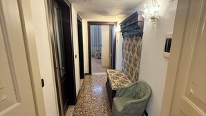 A hallway with a patterned floor, a small seating area with a patterned cushion, and a decorative wall light. - Charming apartment in Venetian palace overlooking the canal, a / c and free wifi! (Venezia)