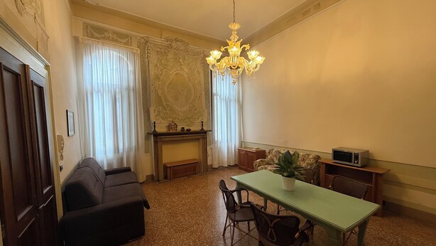 A room with a dining table, chairs, a sofa, a fireplace, and a chandelier. - Charming apartment in Venetian palace overlooking the canal, a / c and free wifi! (Venezia)