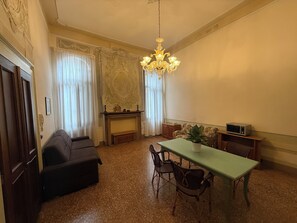A room with a dining table, chairs, a sofa, a fireplace, and a chandelier. - Charming apartment in Venetian palace overlooking the canal, a / c and free wifi! (Venezia)