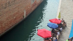 A canal lined with buildings, a narrow waterway, and outdoor seating with umbrellas. - Charming apartment in Venetian palace overlooking the canal, a / c and free wifi! (Venezia)