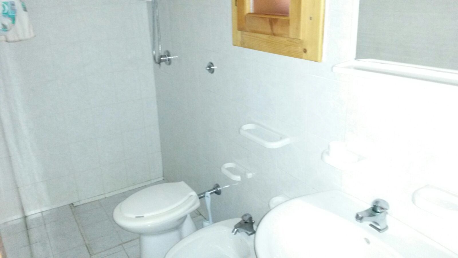 A small, basic bathroom with a toilet, sink, and shower.