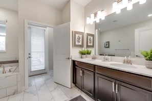 A modern bathroom with a double sink vanity, dark cabinetry, and a large mirror with lights. - Ev7812ha - Champions Gate Resort - 8 Bed 5 Baths Villa (Kissimmee)