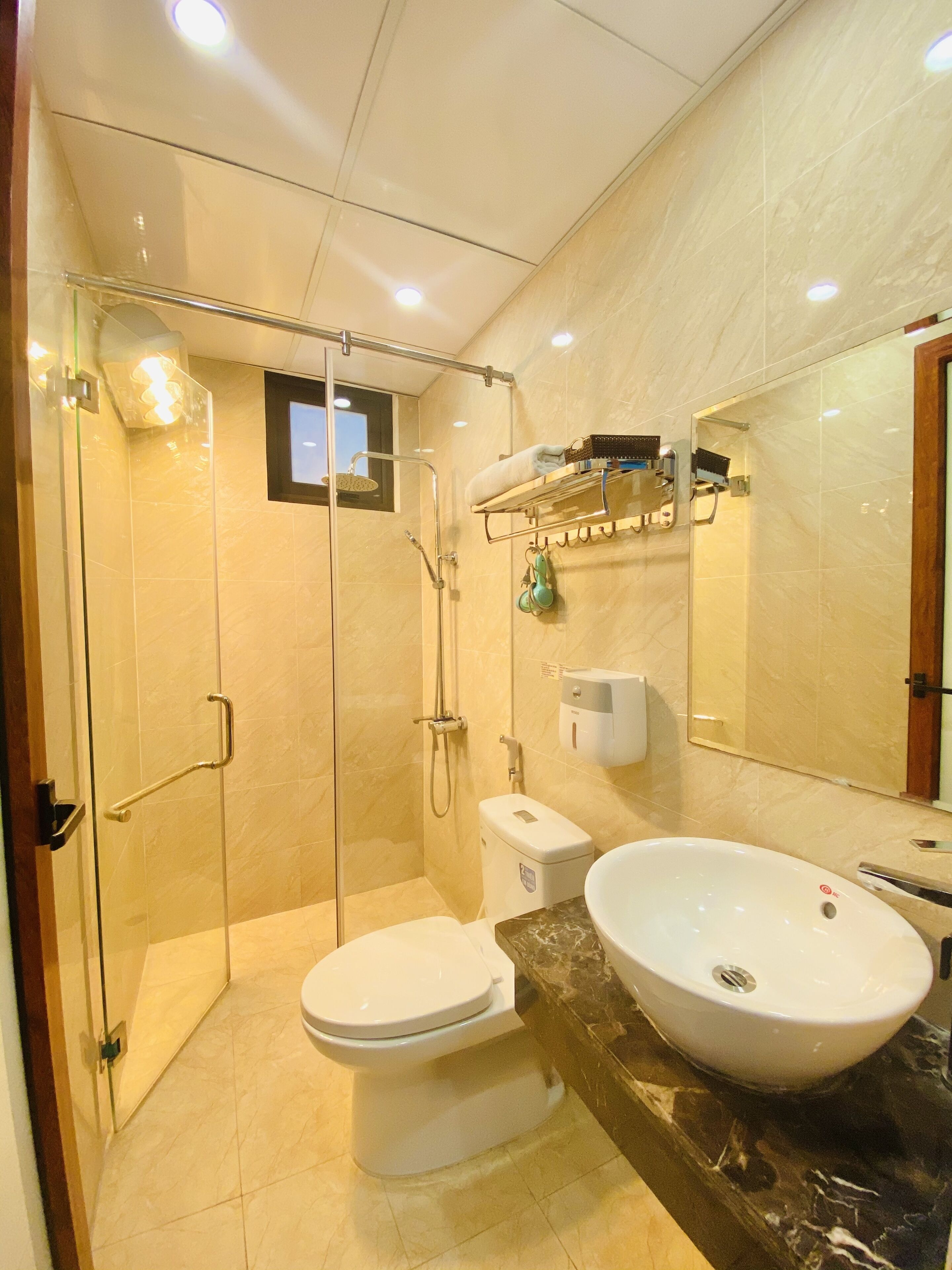 Un baño moderno con ducha de vidrio, inodoro y lavamanos con encimera de mármol.