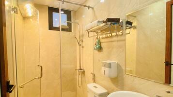 Un baño moderno con ducha de vidrio, inodoro y lavamanos con encimera de mármol.