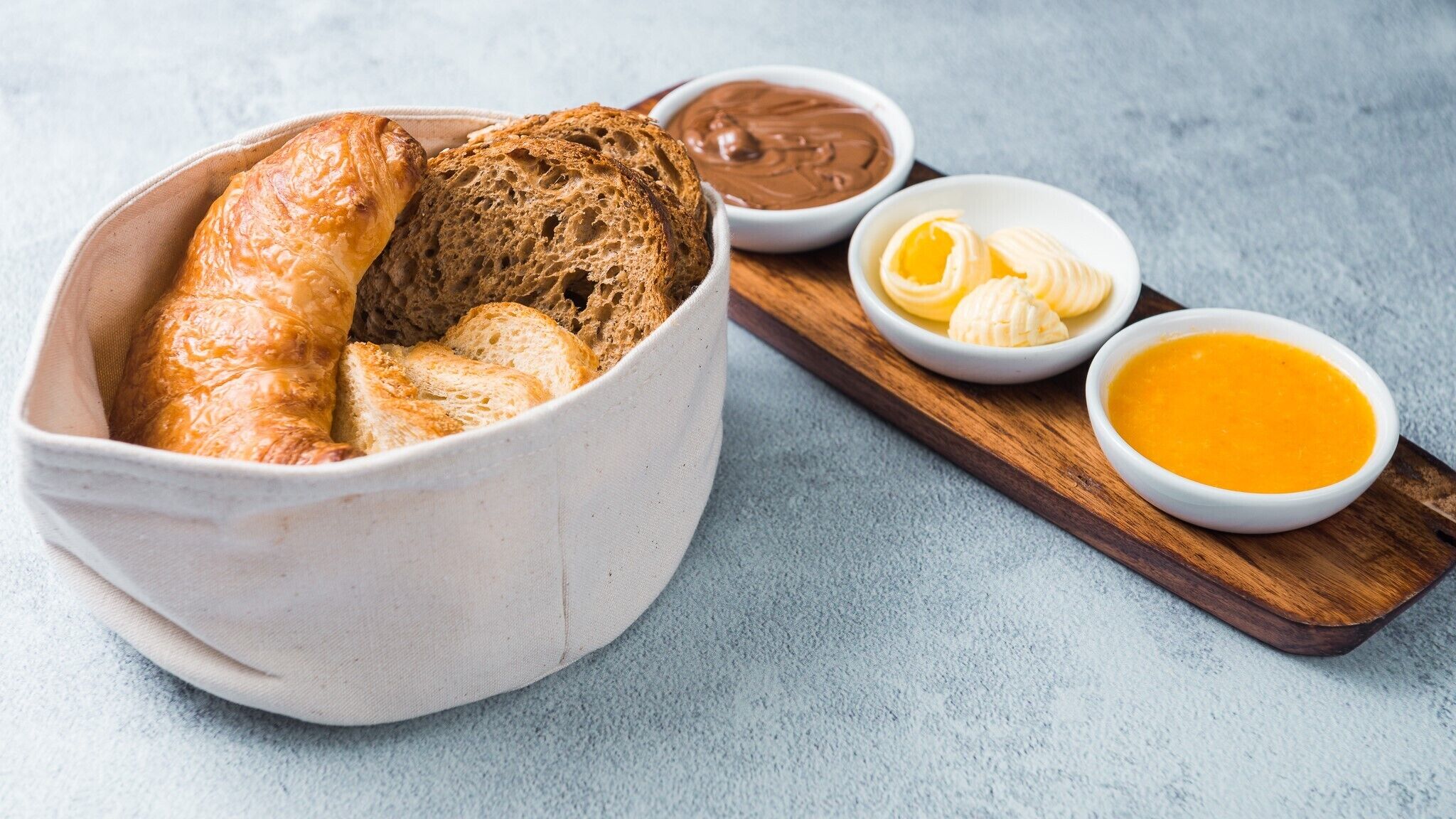 Uma tigela de pão com manteiga e dois tipos de patês.