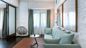 Un salon comprenant un canapé, un fauteuil, une petite table et un grand tableau encadré accroché au mur.