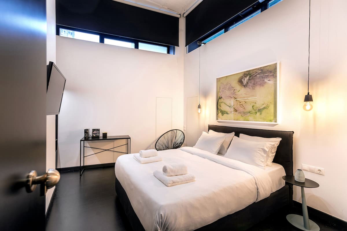 Et moderne hotelværelse med en stor seng, et sengebord, en stol og et billede på væggen.