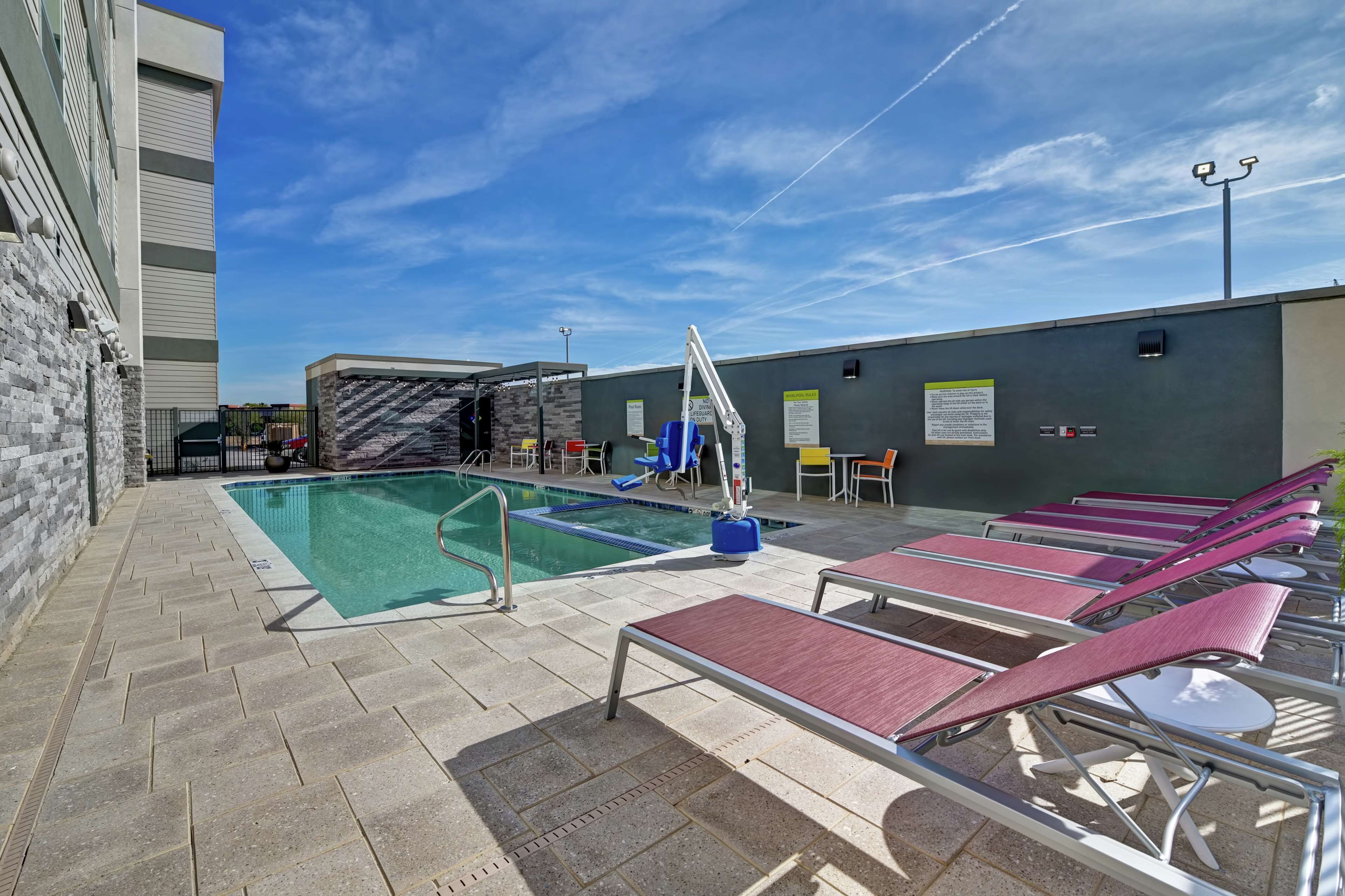 An outdoor pool area with lounge chairs, a water fountain, and a covered seating area.