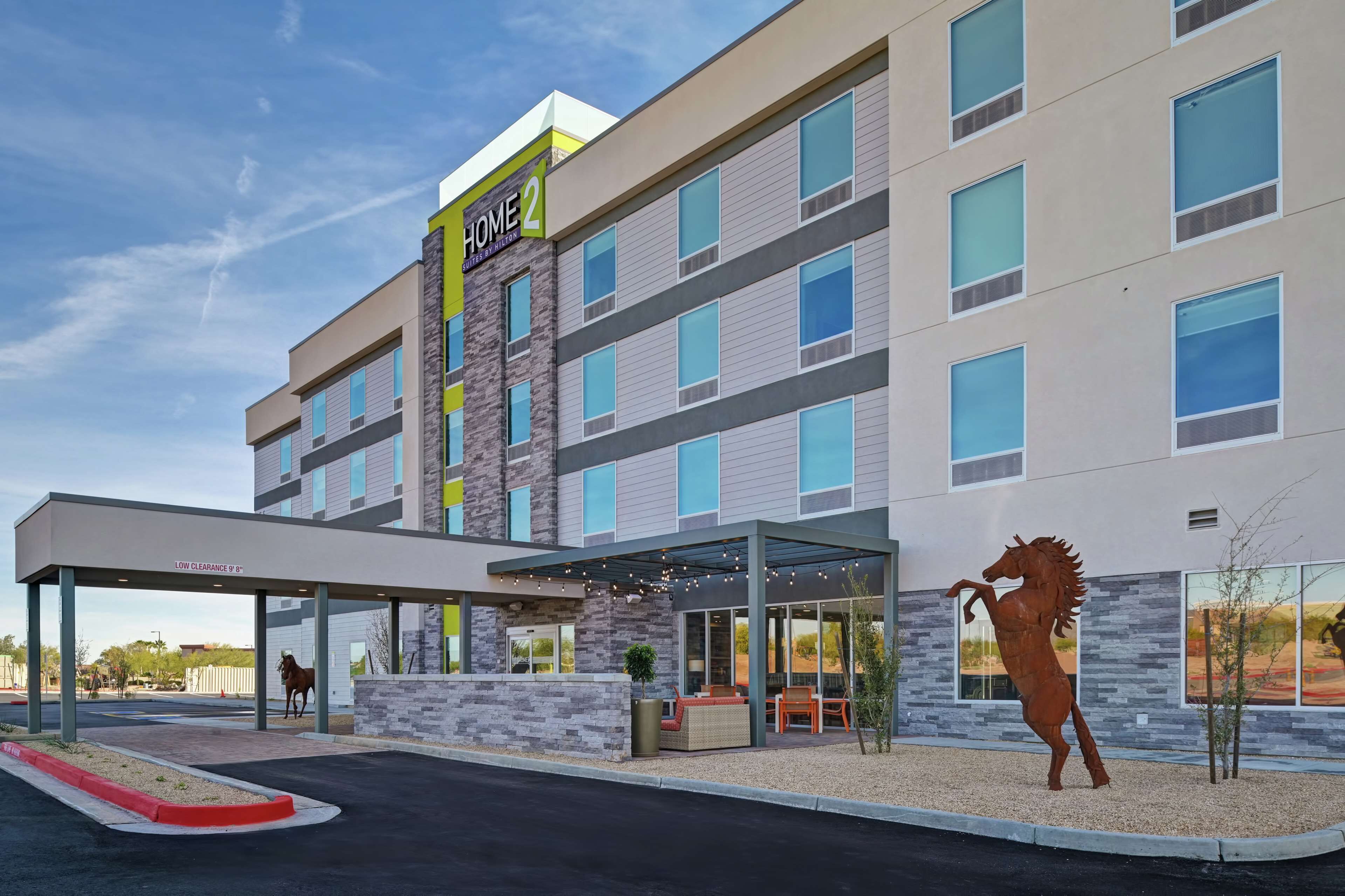 A multi-story hotel with a covered entrance and a horse statue.