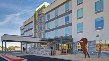 A multi-story hotel with a covered entrance and a horse statue.