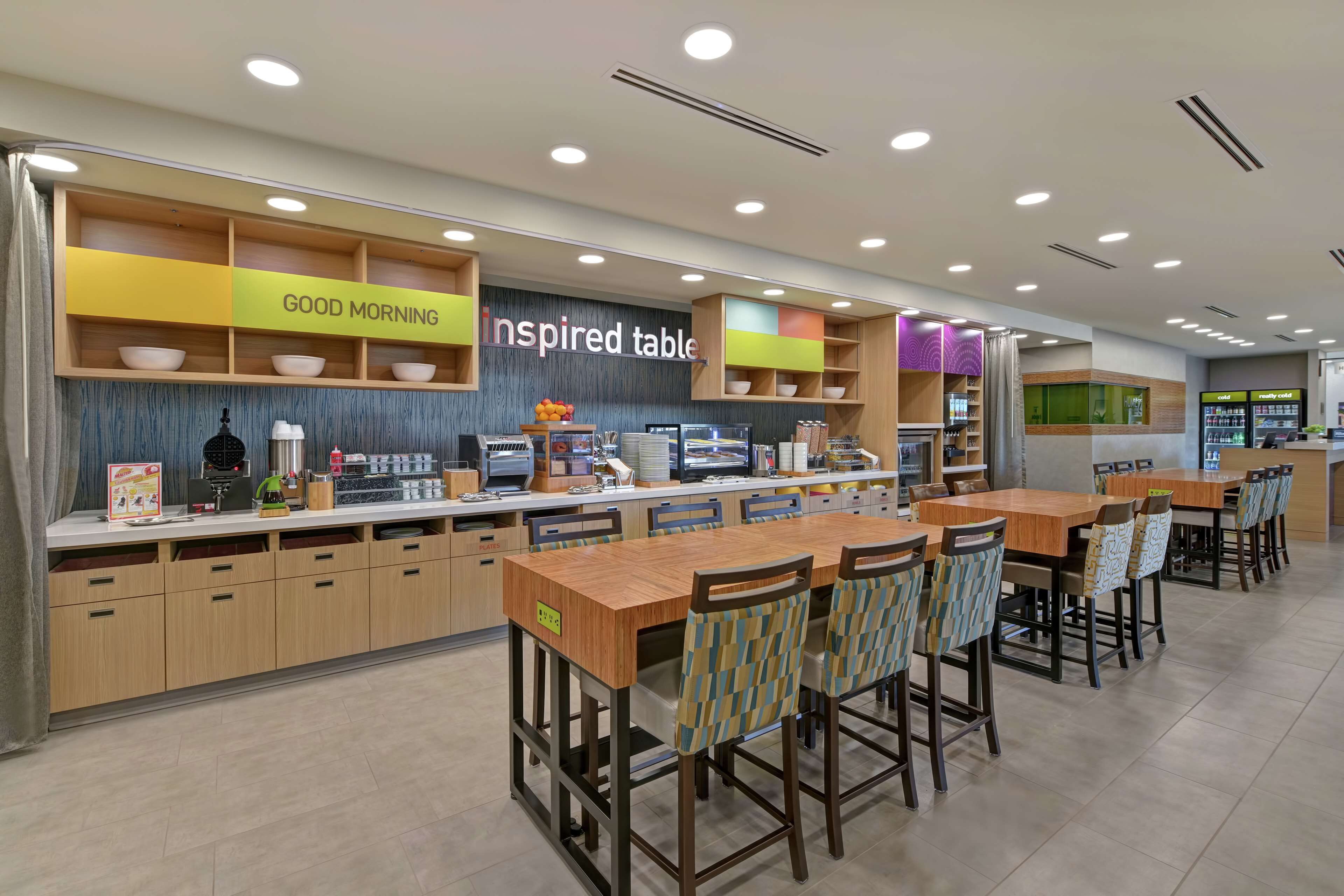 A modern cafe with a wooden counter, bar stools, and a 'Good Morning' sign.