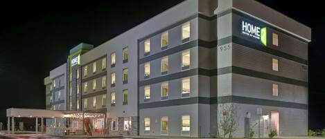 A multi-story hotel with a modern design, featuring a prominent "HOME 2 Suites by Hilton" sign.
