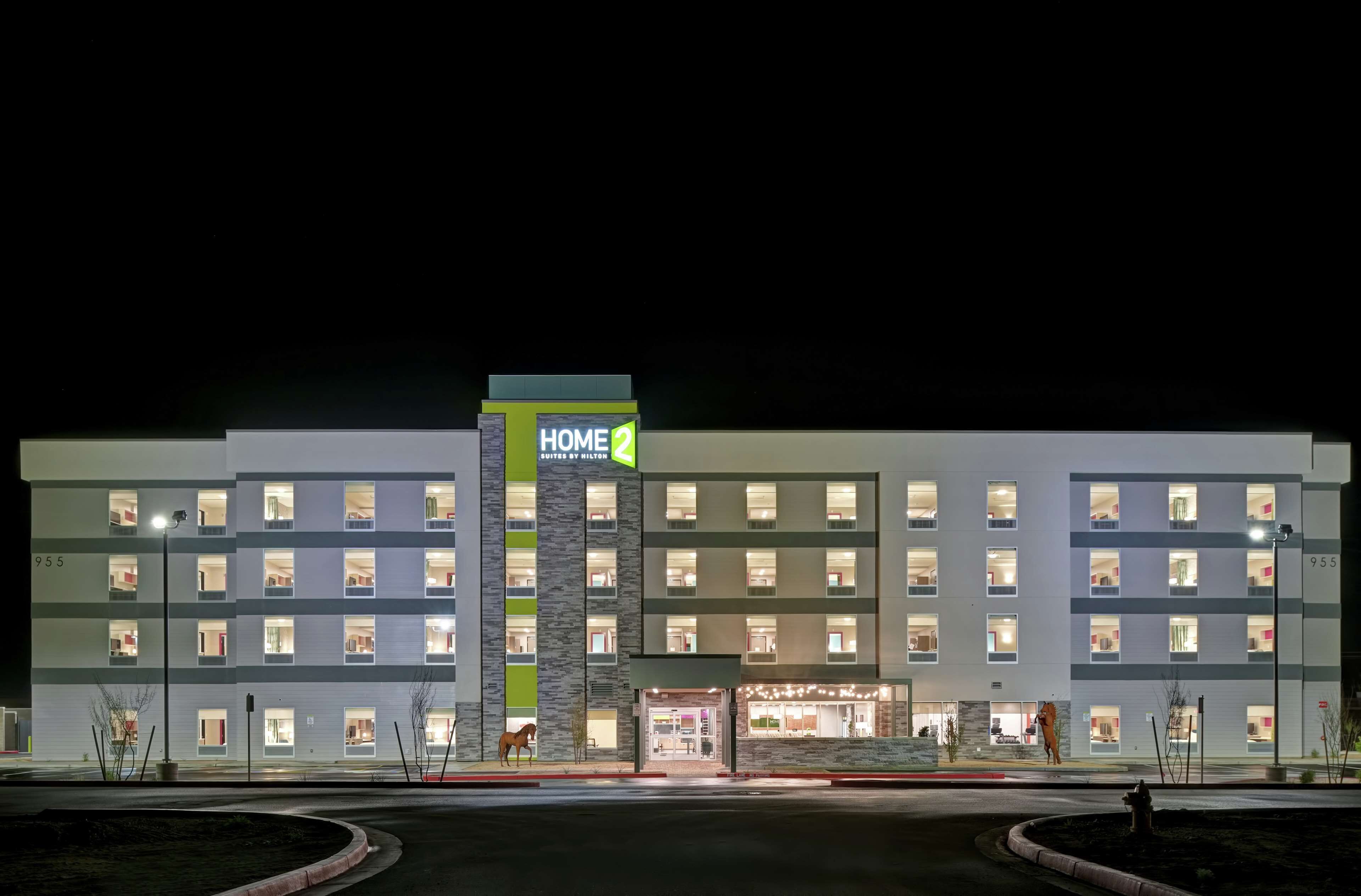 Een meerhoog hotel met een opvallend 'HOME' bord, meerdere balkons en een goed verlichte entree.