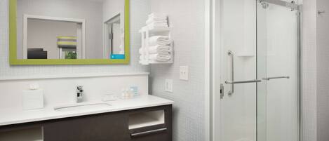 Un baño moderno con un espejo grande, cabina de ducha de vidrio y toallero blanco.