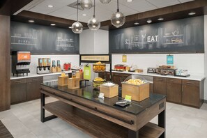 A breakfast bar with various food items and a juice dispenser. - Hampton Inn & Suites Charlotte Airport Lake Pointe (Charlotte)