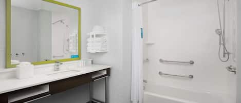 A modern bathroom with a white sink, mirror, and bathtub.