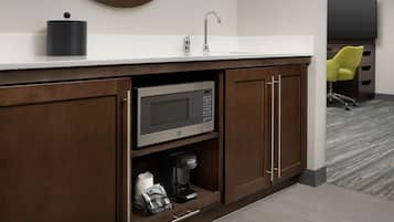 A modern kitchen with a built-in microwave, coffee maker, and a sink with a faucet.