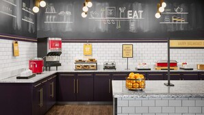 A modern kitchen with a chalkboard wall displaying food items and utensils, a coffee machine, and a breakfast bar. - Hampton Inn & Suites Charlotte Steele Creek (Charlotte)