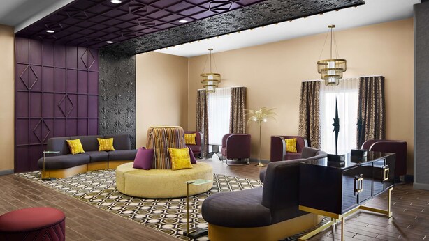 A modern living room with a sofa, ottoman, and armchairs, a black coffee table, and a decorative floor lamp. - Hampton Inn & Suites Charlotte Steele Creek (Charlotte)