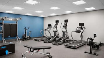 A gym with treadmills, elliptical machines, a bench press, and a weight rack.
