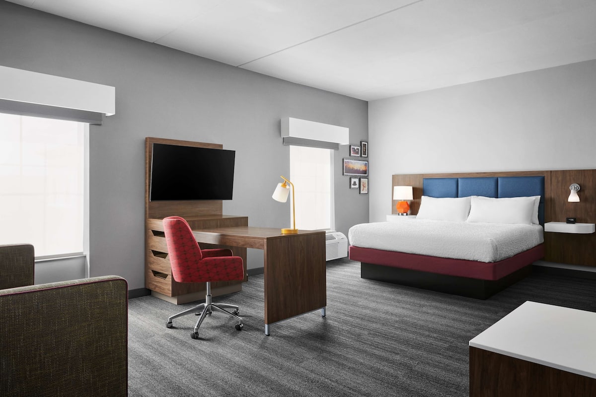 Una habitación de hotel con cama, escritorio, silla y televisión.