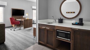 A modern bathroom with a wooden vanity, a round mirror, a sink, and a coffee maker. - Hampton Inn & Suites Charlotte Steele Creek (Charlotte)