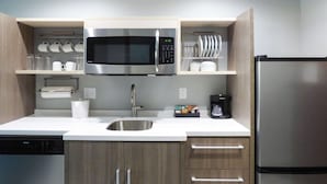 Una cocina moderna con microondas de acero inoxidable, cafetera y refrigerador.