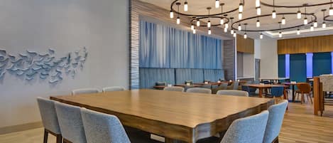 Una sala de conferencias moderna con una amplia mesa de madera, sillas tapizadas en gris y una lámpara de techo original.