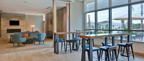 A modern lobby with a bar area, seating, and large windows offering views of the outside.