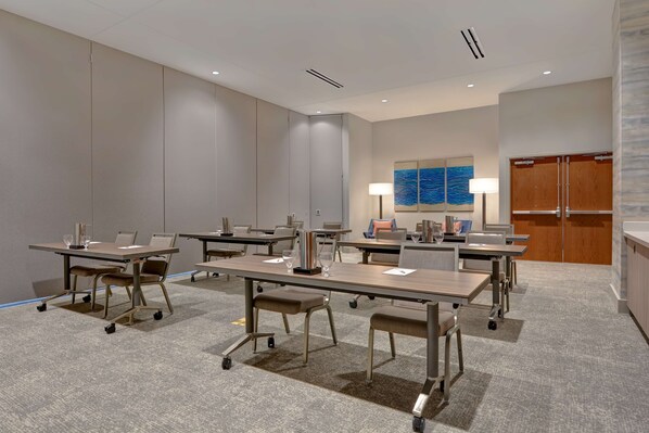 Une salle de conférence dotée de plusieurs tables et chaises, équipée d’ordinateurs portables et de verres.