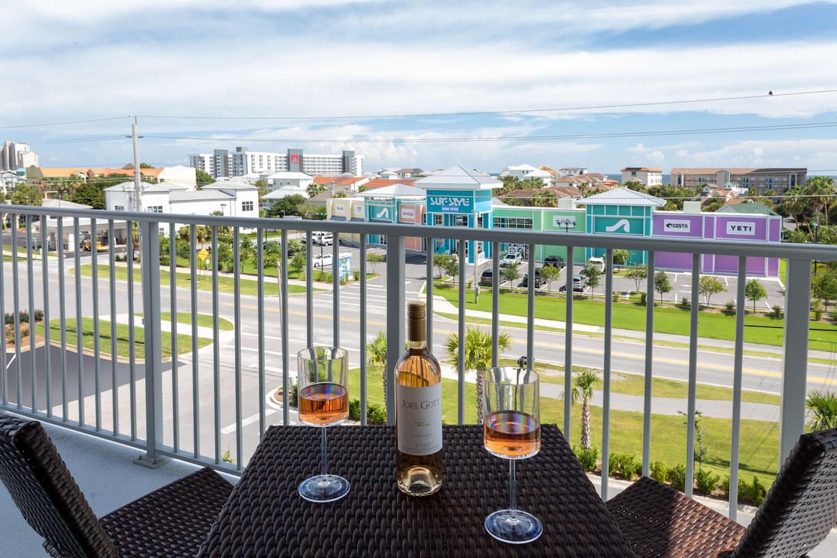 Un balcone con mobili in vimini, una bottiglia di vino e due bicchieri su un tavolino intrecciato.