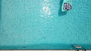 Ein klares, blaues Schwimmbecken mit zwei schwimmenden Liegeflächen und einer Leiter.