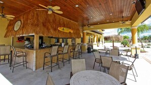 An outdoor bar area with wooden ceiling, thatched roof bar, and multiple seating arrangements. - Ifr7821ha - Paradise Palms Resort - 6 Bed 5 Baths Villa (Kissimmee)