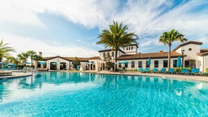 A swimming pool with lounge chairs and umbrellas, surrounded by buildings with a Mediterranean architectural style. - Ev7820ha - Windsor At Westside Resort - 10 Bed 6 Baths Villa (Kissimmee)