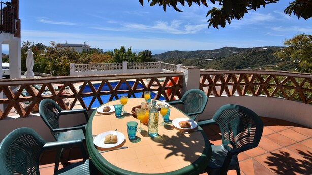 A terrace with a table set for breakfast overlooking a pool and hills. - Casa Carrerilla (Frigiliana)