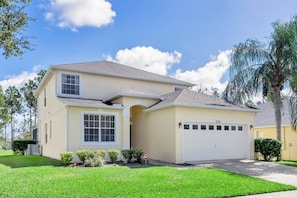 A two-story house with a garage, a well-maintained lawn, and a palm tree in the background.
