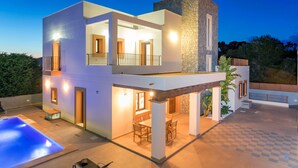 A modern two-story house with a swimming pool, outdoor seating, and a stone facade. - Villa Near Ibiza Town Sleeps 12/14 (Cap Martinet)