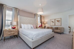 A hotel room with a large bed, a bedside table with a lamp, a chair, and framed artwork on the wall. - Ev7833ha - Champions Gate Resort - 6 Bed 5 Baths Villa (Davenport)